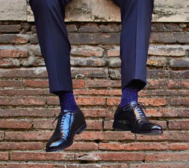 Uomo con calzini blu a pois bianchi e scarpe nere lucide. Un perfetto abbinamento calzini scarpe uomo per un look elegante.