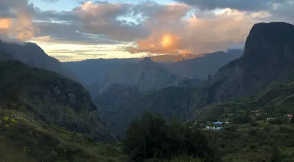 Al tramonto, le montagne della "diagonale des fous" si tingono di rosa. Un villaggio si intravede tra le valli verdi.